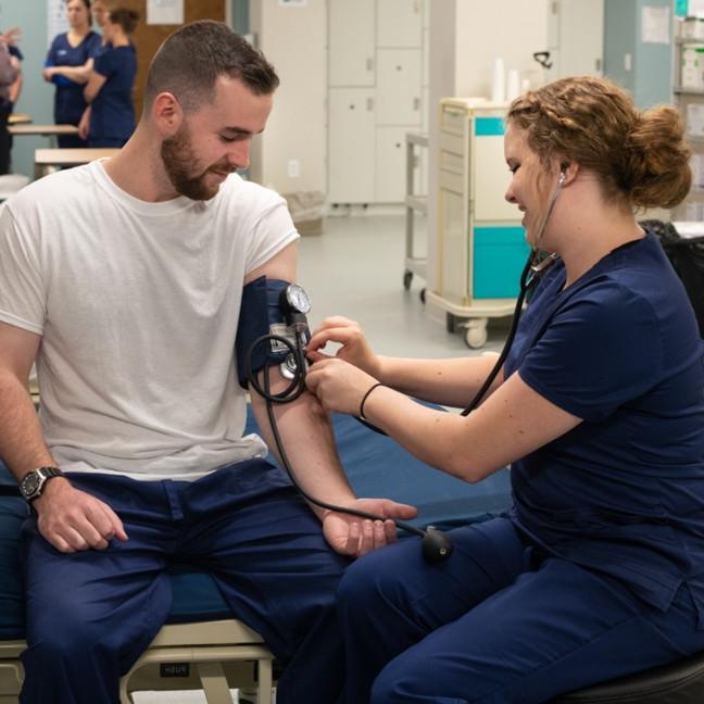 a female student takes the blood pressure of a male student